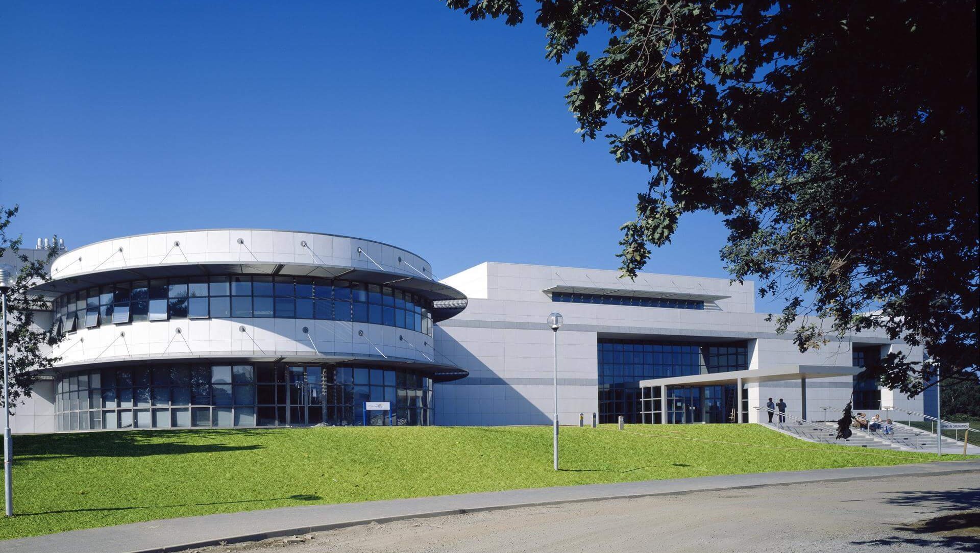 A picture of the conway institute. It is a two story white building with a circular section at the front. In front of the building, there is a grass verge.